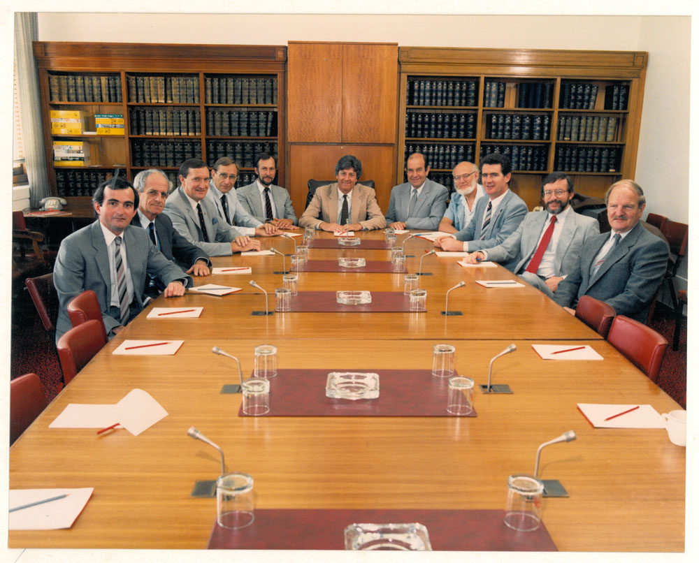 Standing Committee on Industry, Science and Technology, December 1987. L-R: Derek Drinkwater [Research Officer], Senators Bryant Burns, David Brownhill and Peter Baume, Peter Keele [Secretary], Senators Bruce Childs [Chair], Brian Archer, John Coulter, Jim McKiernan and Peter Cook, and Michael Game [Research Officer].