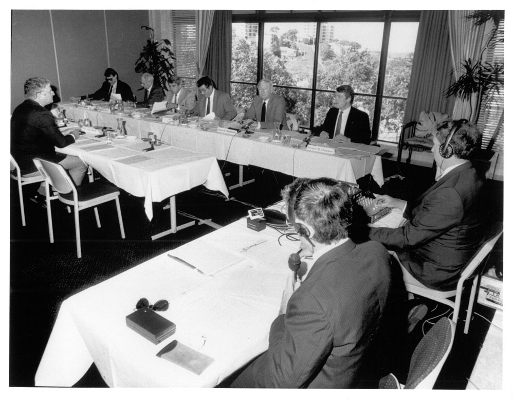 Standing Committee on Transport, Communications and Infrastructure hearing evidence from witness Captain David Jenner [Director, Challenge Air Services] at a public hearing in Coolangatta, Qld, of its inquiry into the organisation and operations of the Federal Airports Corporation and the Civil Aviation Authority, 20 July 1989. Senators L-R: John Faulkner and Bryant Burns, Tony Magi [Secretary], Senators Dominic Foreman [Chair], David MacGibbon and Grant Chapman.