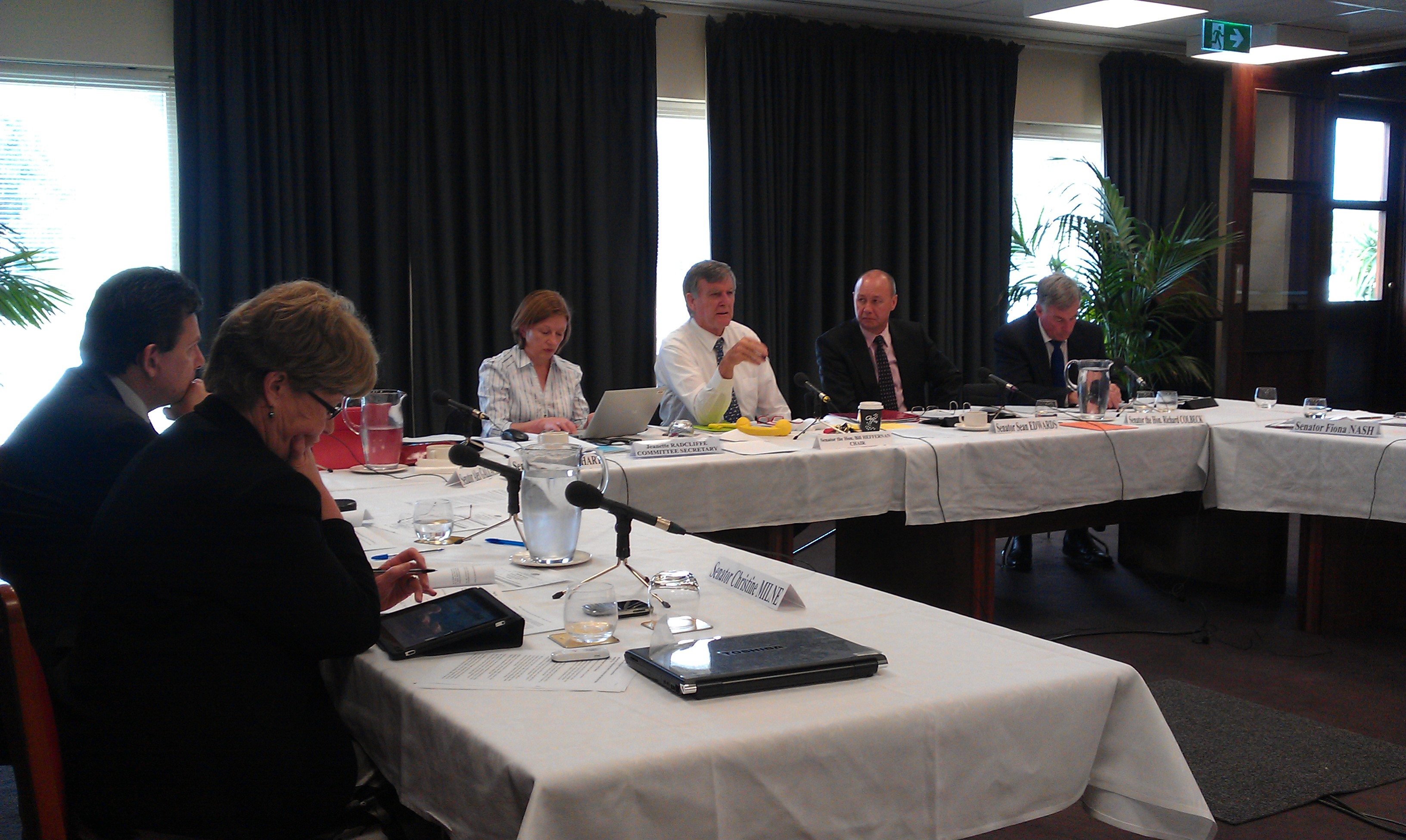 \x3cp\x3eCommittee hearing, Private Members Dining Room, Old Parliament House, Canberra, 16 November 2011. L-R: Senators Christine Milne and Nick Xenophon, Jeanette Radcliffe [Committee Secretary], Senators Bill Heffernan [Chair], Sean Edwards, Richard Colbeck, Fiona Nash, Barbaby Joyce and Judith Adams. Foreground: Wayne Van Balen [witness].\x3c/p\x3e